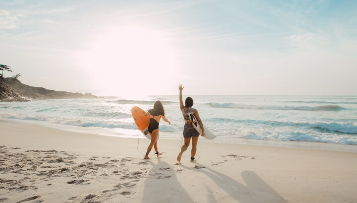 mujeres-en-la-playa-con-una-tabla-de-surf